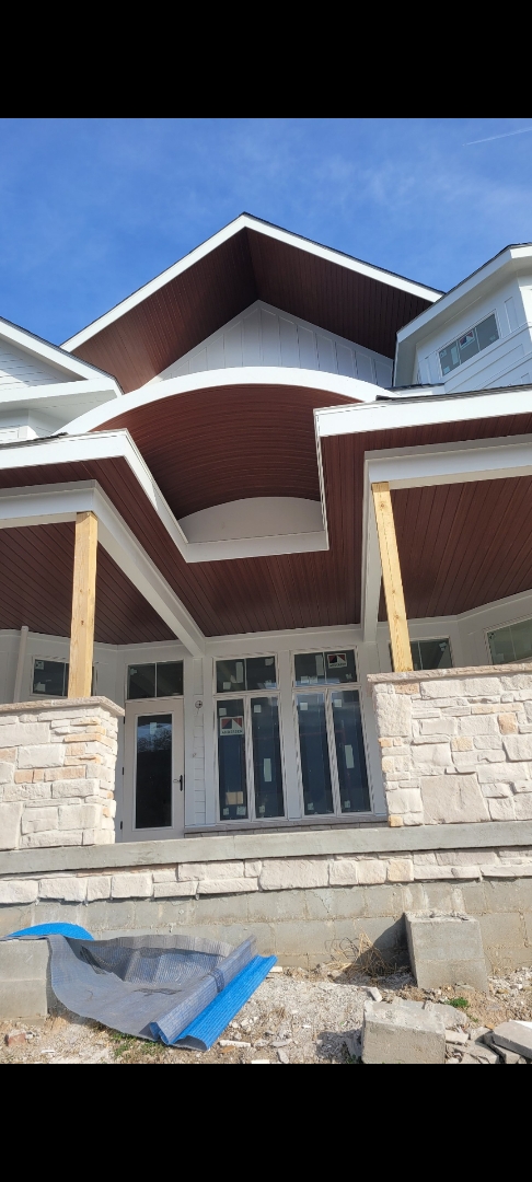 Custom home after siding install with curved porch roof and stone