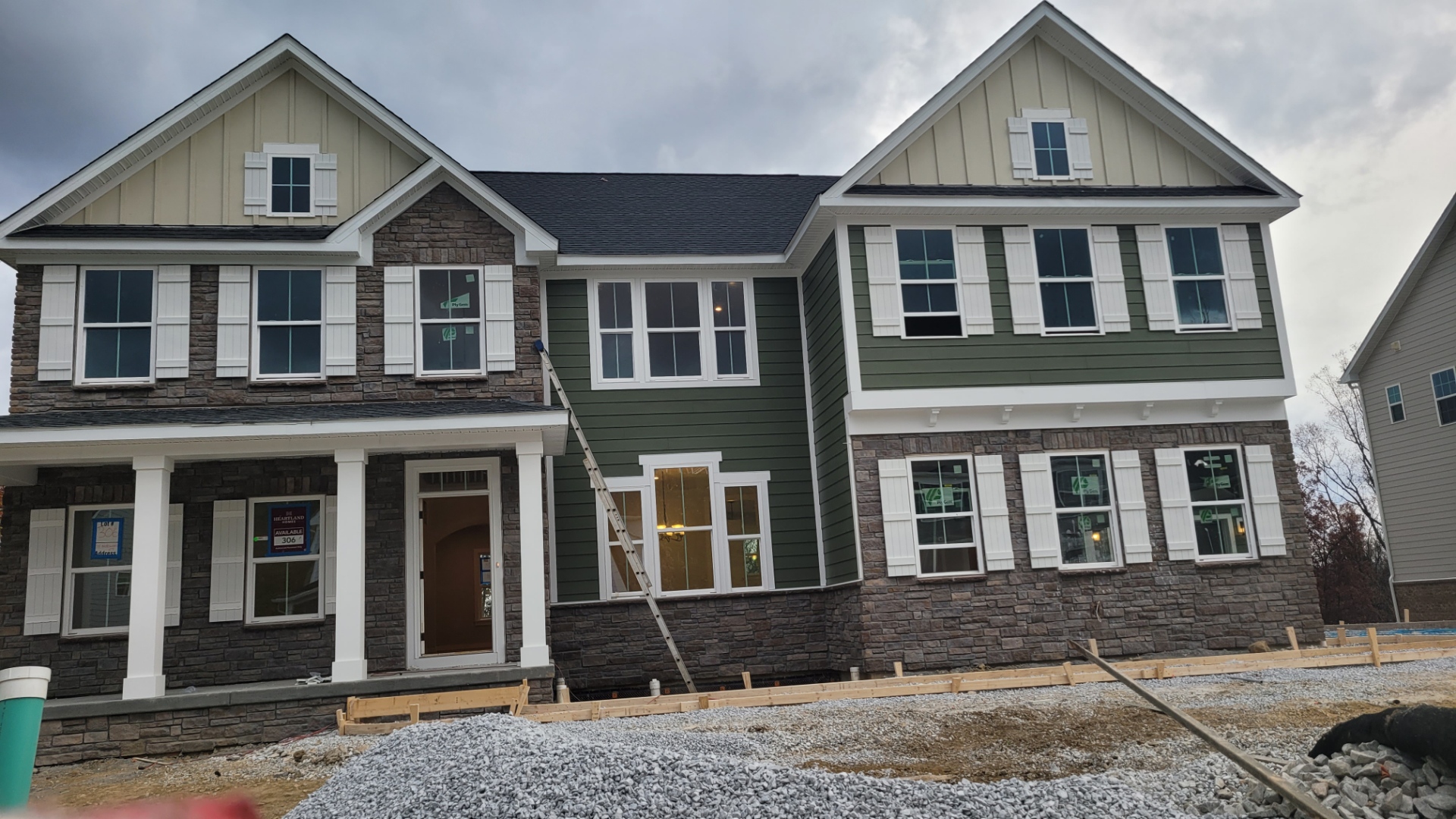 New construction home with green board and batten siding and stone accents